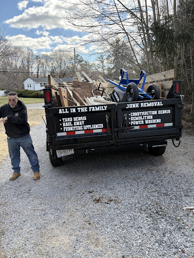 All In The Family Junk Removal dump trailer loaded with yard debris, furniture, and household junk on Long Island